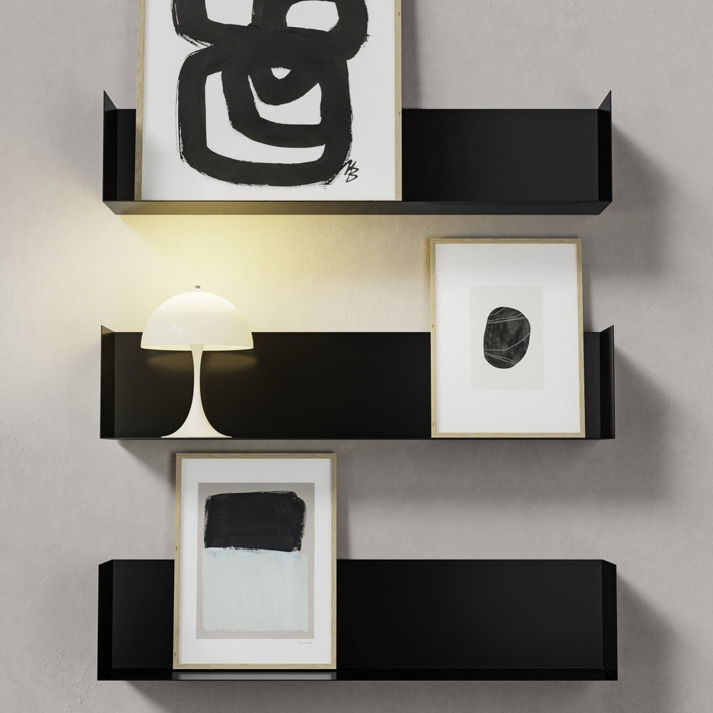 Drei Wandregale in schwarz, dekoriert mit gerahmten Bildern und einer Lampe